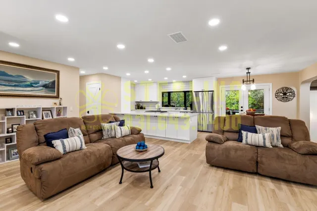 a kitchen that has a refrigerator a stove and white cabinets with wooden floor