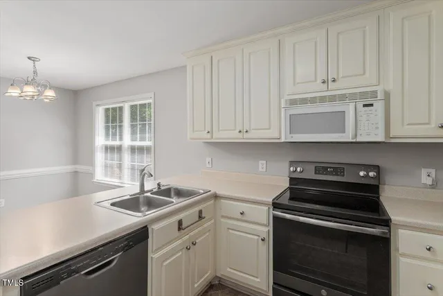 a kitchen with granite countertop a sink dishwasher stove and white cabinets