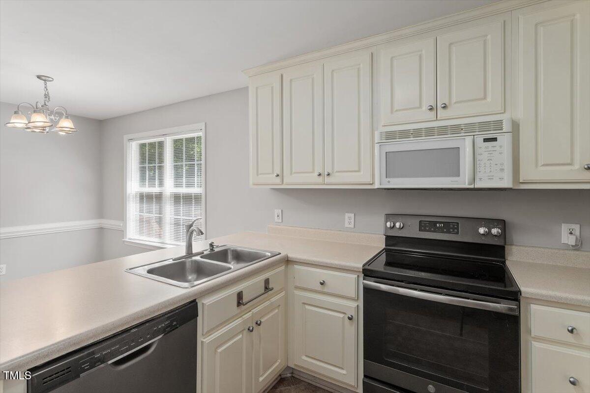 212 Webfoot Drive Garner, NC 27529 - Photo 12 of 26 a kitchen with granite countertop a sink dishwasher stove and white cabinets