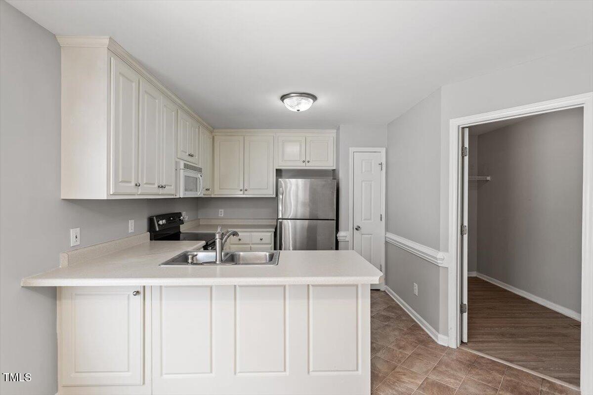 212 Webfoot Drive Garner, NC 27529 - Photo 9 of 26 a kitchen with white cabinets and stainless steel appliances