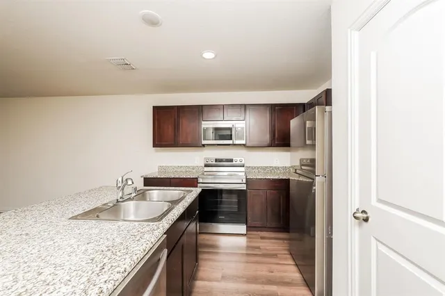 a kitchen with stainless steel appliances granite countertop a sink stove and refrigerator
