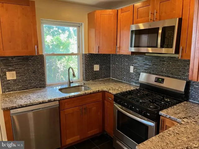 a kitchen with granite countertop a stove sink and microwave