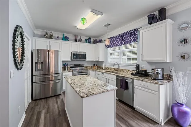 a kitchen with a refrigerator a stove a sink cabinets and wooden floor