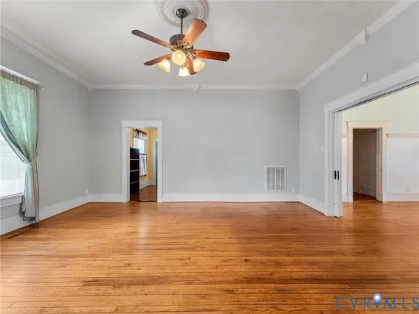 a view of an empty room with window and wooden floor