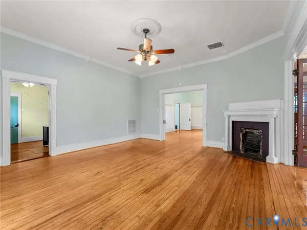 a view of an empty room with wooden floor and a fireplace
