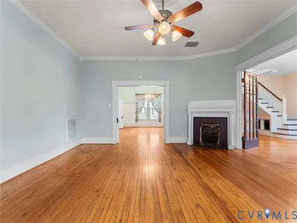 a view of an empty room with wooden floor fireplace and a window