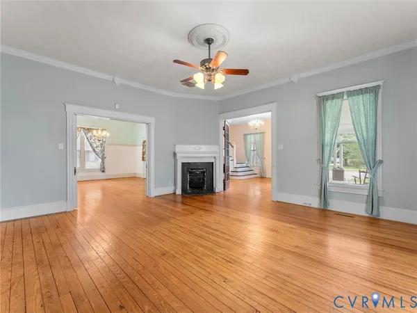 a view of an empty room with wooden floor fireplace and a window