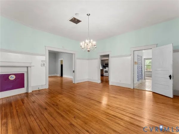 a view of a room with wooden floor and chandelier