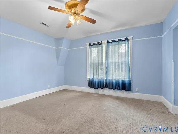 an empty room with a window and a chandelier fan