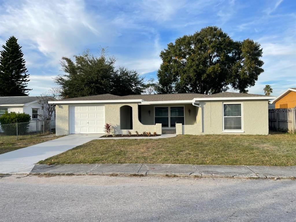 7411 Oak Crest Drive Port Richey, FL 34668 - Photo 1 of 1 a front view of a house with a yard and garage