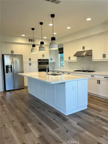 a large kitchen with stainless steel appliances kitchen island granite countertop a stove a sink and a refrigerator