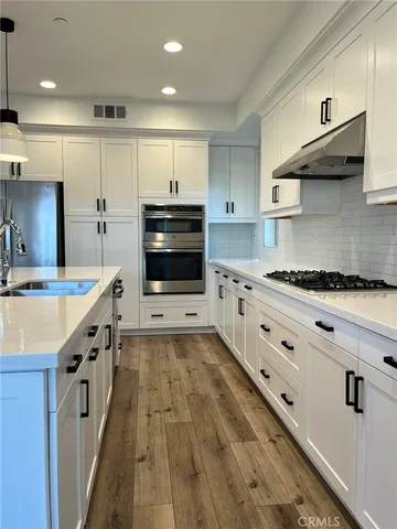 a large kitchen with stainless steel appliances kitchen island granite countertop a stove and a sink
