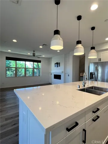 a large kitchen with kitchen island a stove a center island a sink and a wooden floor