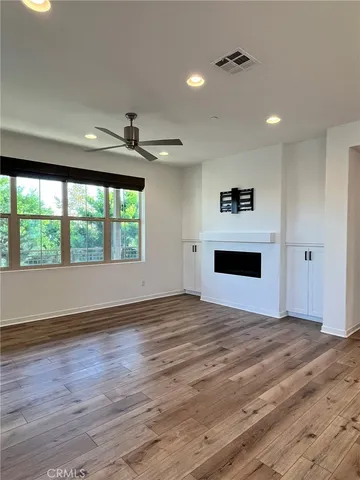 a view of an empty room with a window and a kitchen