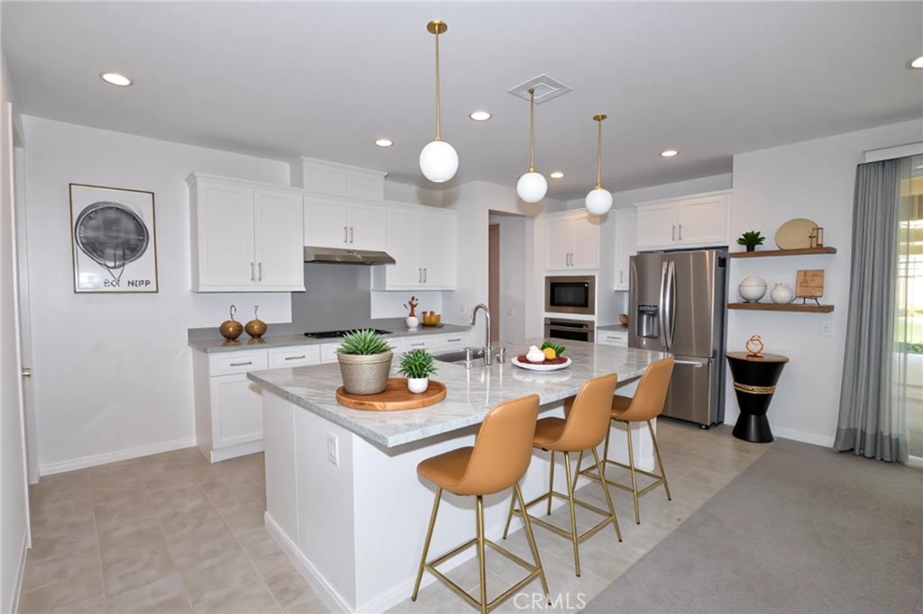 39824 Ninebark Court Temecula, CA 92591 - Photo 3 of 32 a kitchen with stainless steel appliances granite countertop a stove top oven a refrigerator a sink and a dining table with white cabinets