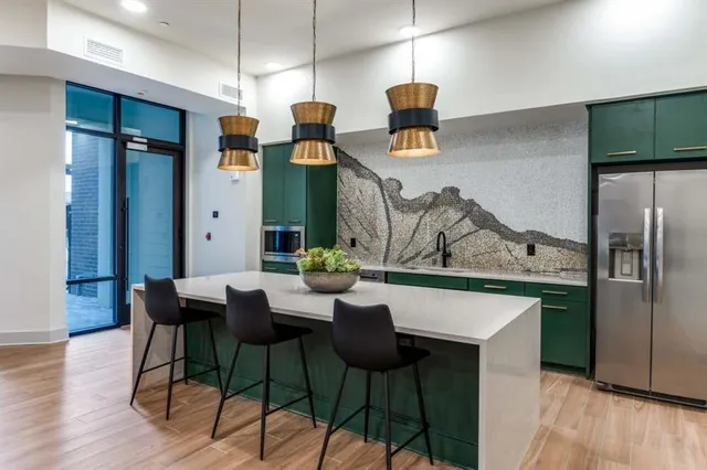 a kitchen with stainless steel appliances kitchen island a table chairs in it and wooden floors