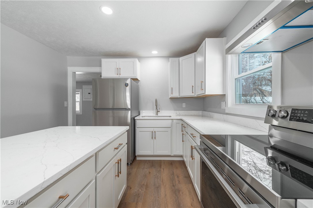 218 Roxboro Road Vermilion, OH 44089 - Photo 16 of 50 Kitchen with appliances with stainless steel finishes, range hood, light stone countertops, white cabinetry, and recessed lighting