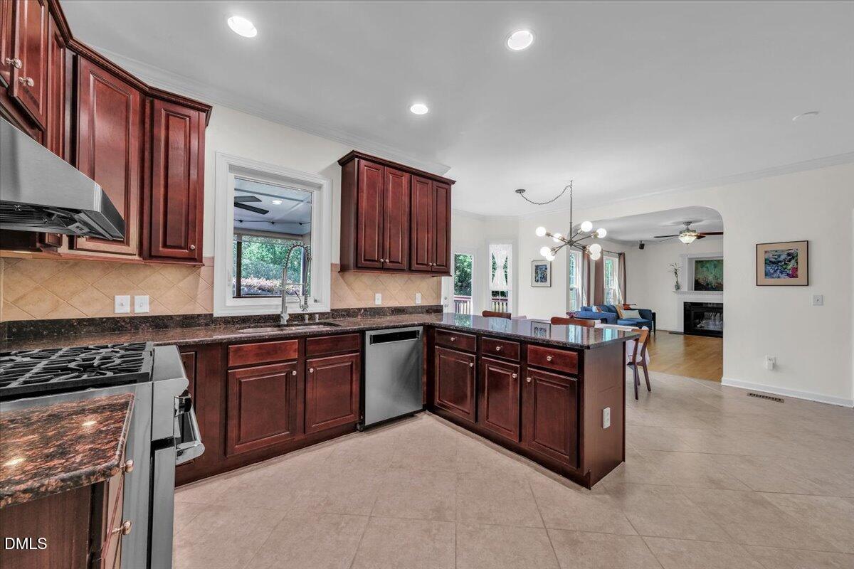 2908 Oak Bridge Drive Raleigh, NC 27610 - Photo 13 of 47 a kitchen with stainless steel appliances granite countertop a stove a sink dishwasher and a refrigerator with wooden cabinets