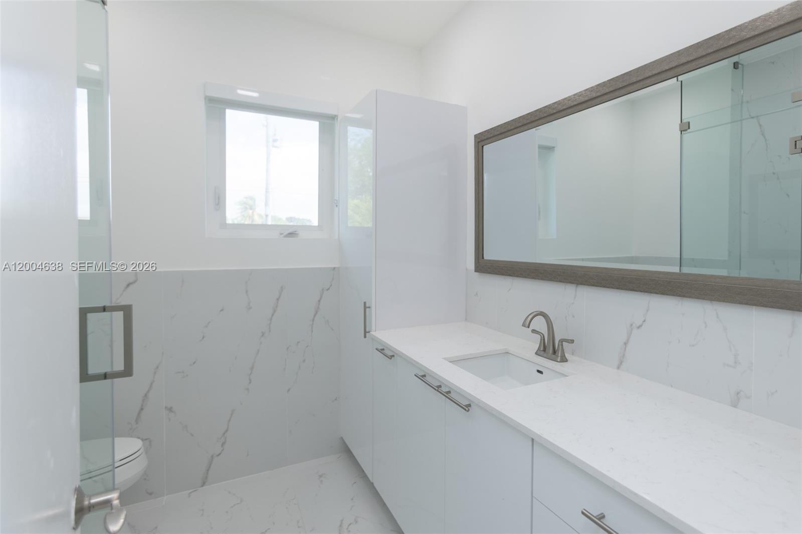 1690 Daytonia Road Miami Beach, FL 33141 - Photo 43 of 88 a bathroom with a sink and mirror with toilet