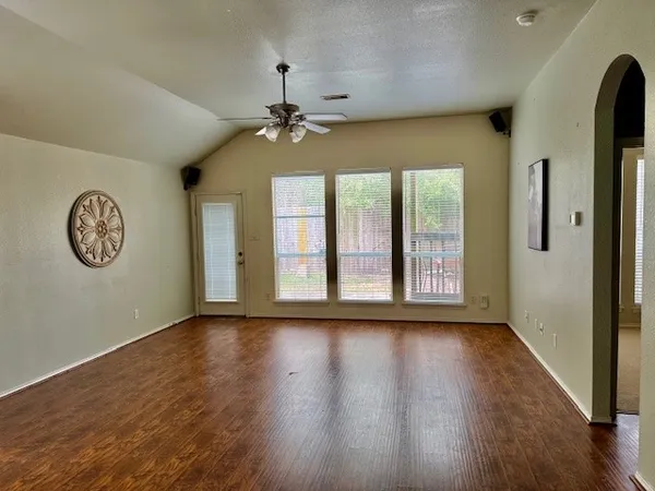 a view of an empty room with a window and wooden floor