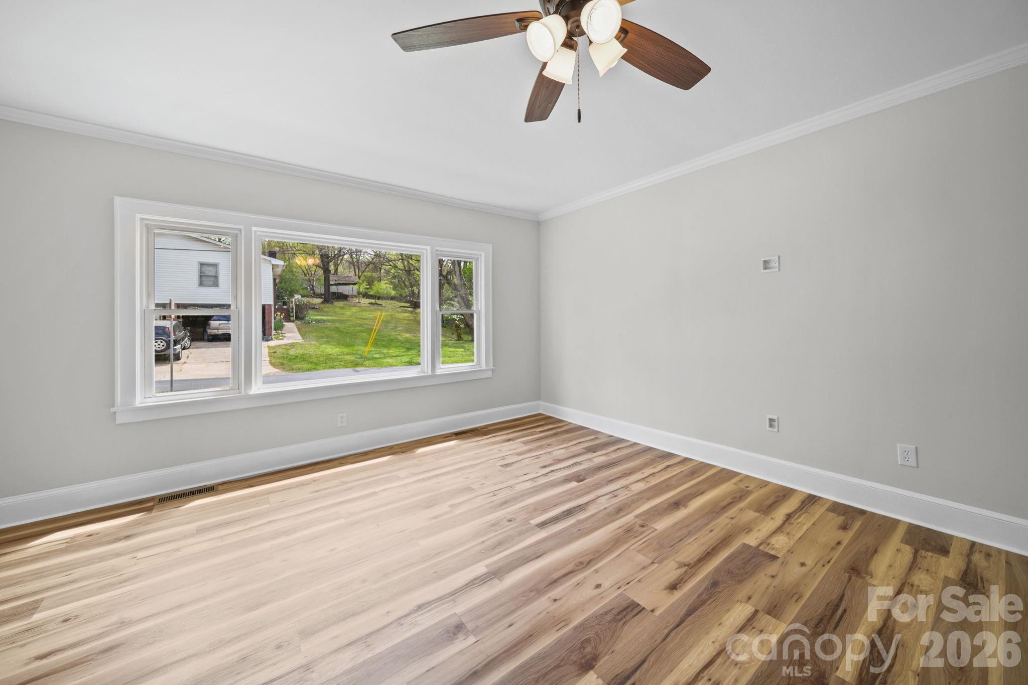 196 Spruce Street Badin, NC 28009 - Photo 9 of 43 a view of an empty room with a window and wooden floor