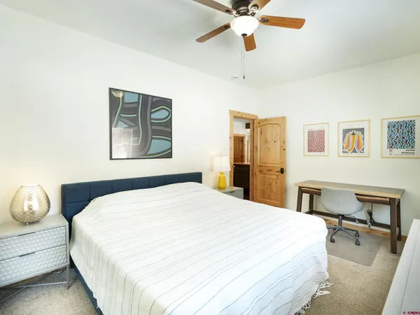 a bedroom with a large bed and a chandelier fan