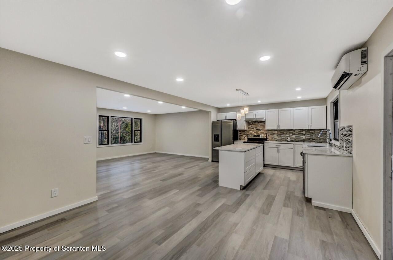 71 Sandy Beach Road Gouldsboro, PA 18424 - Photo 8 of 57 a large kitchen with kitchen island a sink a stove a refrigerator and white cabinets with wooden floor