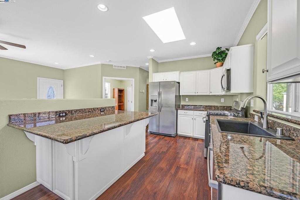 3263 Vineyard Avenue Pleasanton, CA 94566 - Photo 2 of 14 a kitchen with stainless steel appliances granite countertop a sink dishwasher stove and oven with wooden floor