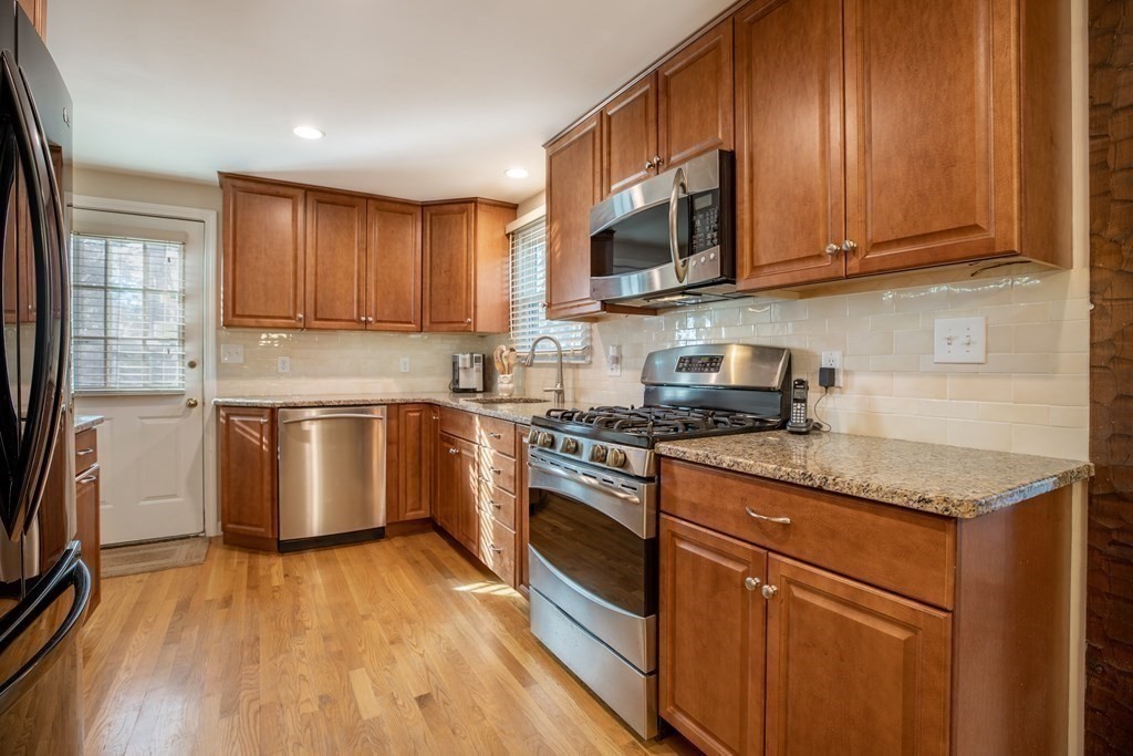 1 Spring Lane Sharon, MA 02067 - Photo 3 of 23 a kitchen with granite countertop wooden floors stainless steel appliances and sink