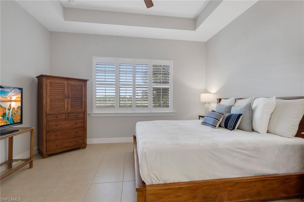 6809 Bequia Way Naples, FL 34113 - Photo 15 of 46 Bedroom with a raised ceiling, light tile patterned floors, and ceiling fan