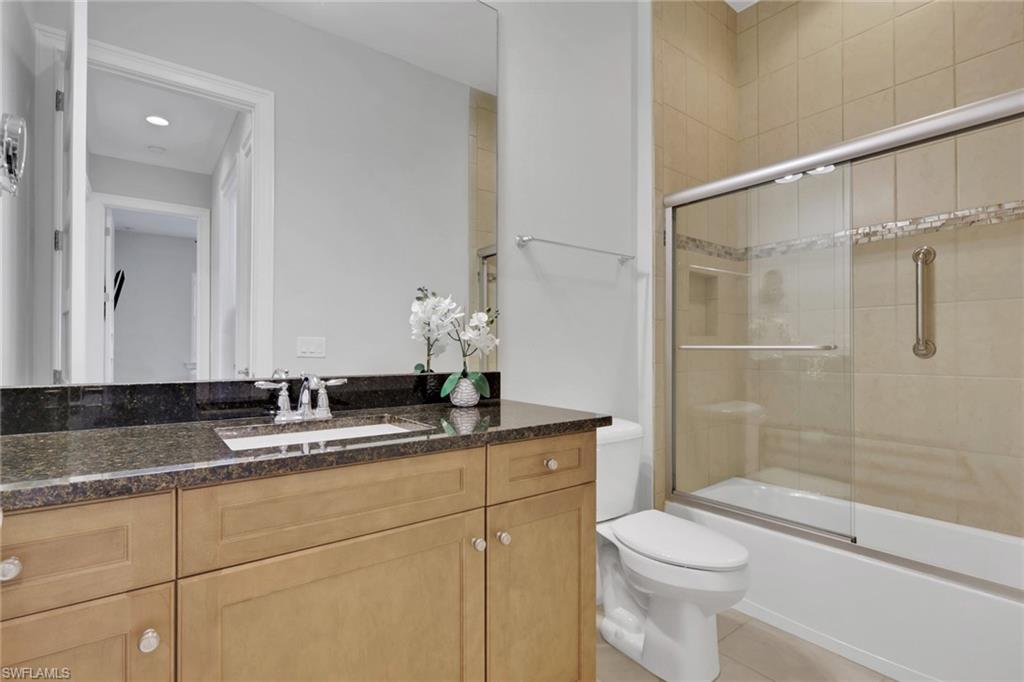 6809 Bequia Way Naples, FL 34113 - Photo 18 of 46 Full bathroom with vanity, shower / bath combination with glass door, and light tile patterned flooring