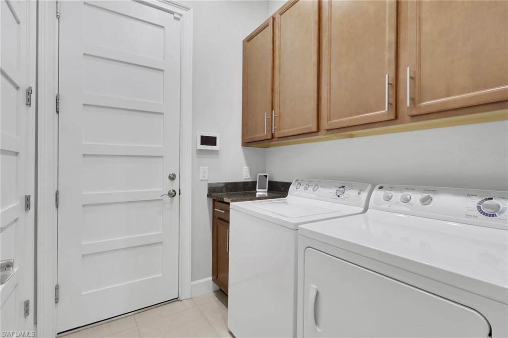 6809 Bequia Way Naples, FL 34113 - Photo 19 of 46 Laundry area with light tile patterned flooring, separate washer and dryer, and cabinet space