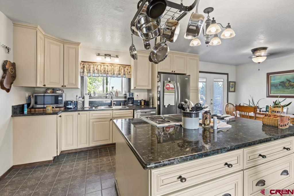 15567 6282nd Road Montrose, CO 81403 - Photo 6 of 36 a kitchen with granite countertop a sink a window stainless steel appliances and cabinets