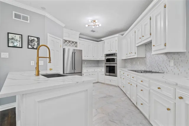 a large white kitchen with granite countertop a sink a stove a refrigerator and cabinets