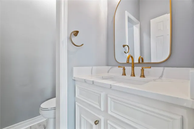 a bathroom with a granite countertop toilet sink and mirror