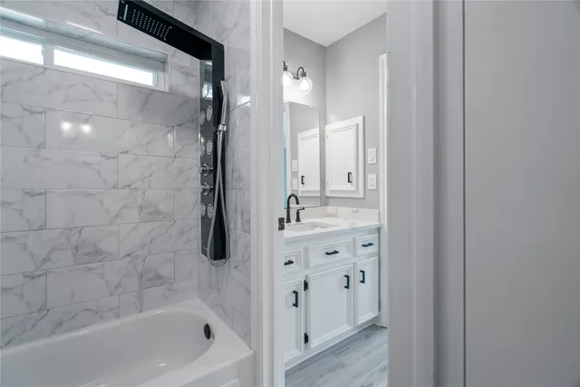 a bathroom with a granite countertop sink a mirror and a bathtub