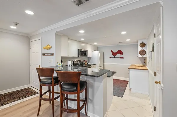 a dining room with stainless steel appliances kitchen island granite countertop a dining table chairs and a refrigerator