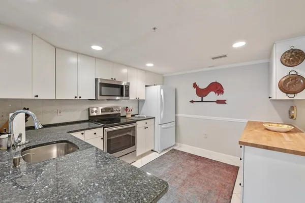 a kitchen with stainless steel appliances granite countertop a sink and a stove top oven with wooden floor