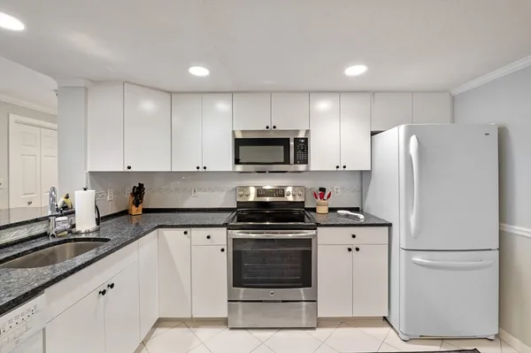 a kitchen with granite countertop white cabinets and refrigerator stove a sink and dishwasher