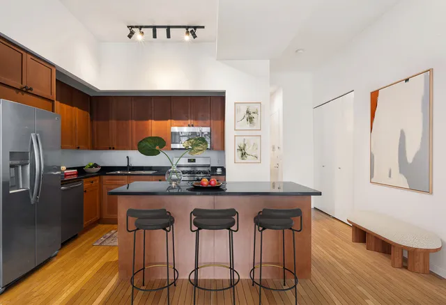 a kitchen with stainless steel appliances a dining table chairs and wooden floor