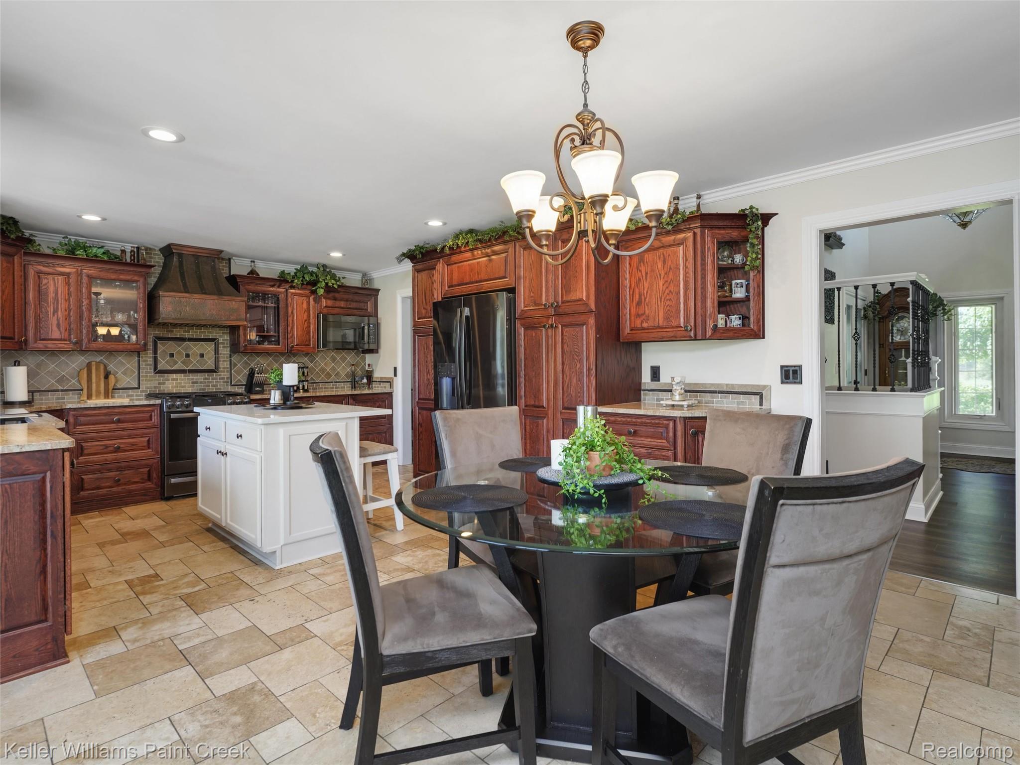 5813 36 Mile Road Romeo, MI 48065 - Photo 12 of 81 Kitchen featuring rich wood cabinetry, a central white island, stainless steel appliances, and a decorative tile backsplash