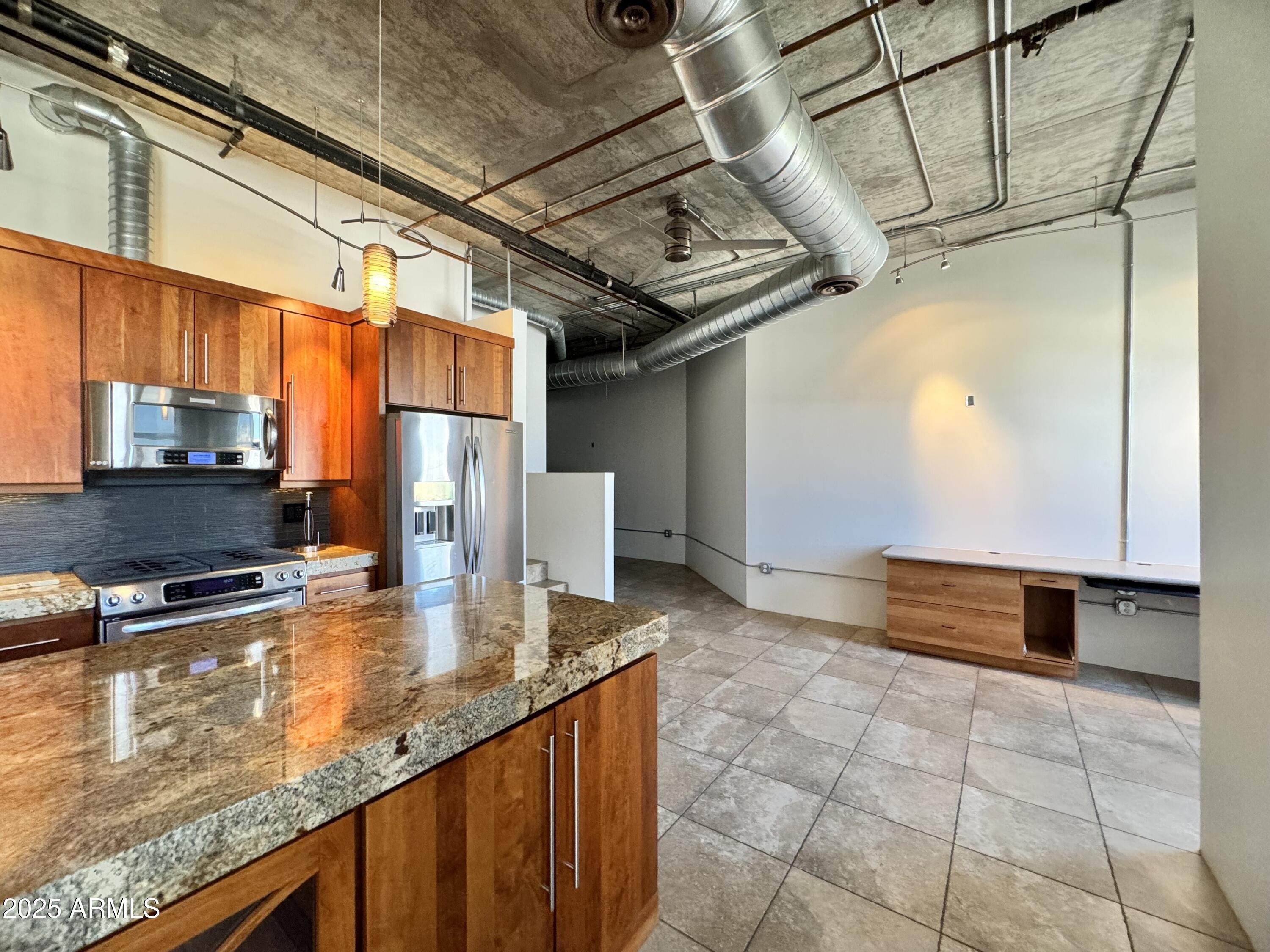 21 East 6th Street, Unit 306 Tempe, AZ 85281 - Photo 12 of 17 a kitchen with stainless steel appliances granite countertop a stove a sink and a microwave