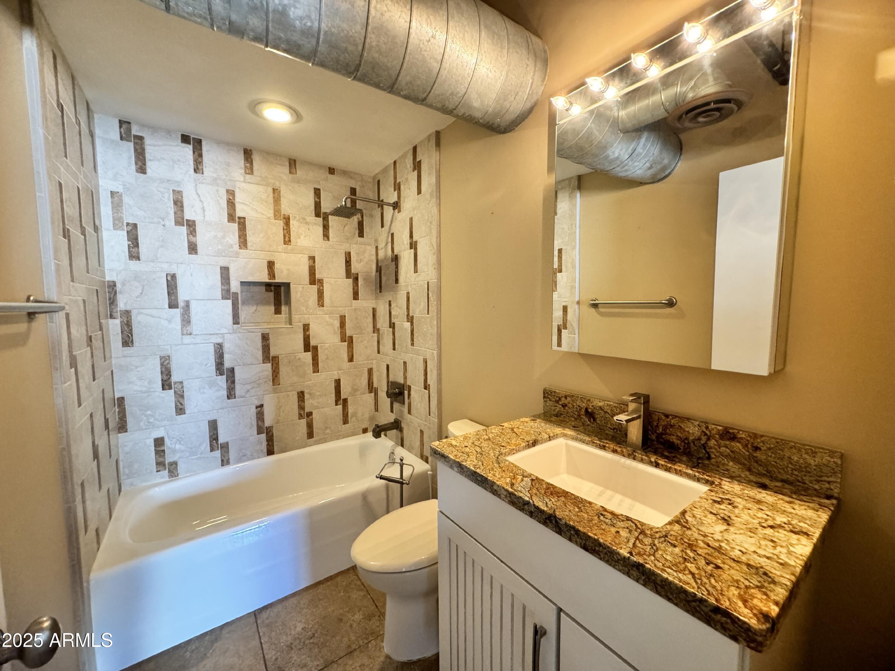 21 East 6th Street, Unit 306 Tempe, AZ 85281 - Photo 15 of 17 a bathroom with a granite countertop sink a toilet a mirror a bathtub and shower
