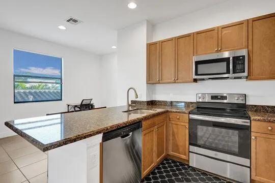 a kitchen with granite countertop a sink stove and microwave