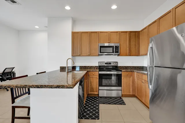 a kitchen with granite countertop a refrigerator stove top oven a sink and dishwasher