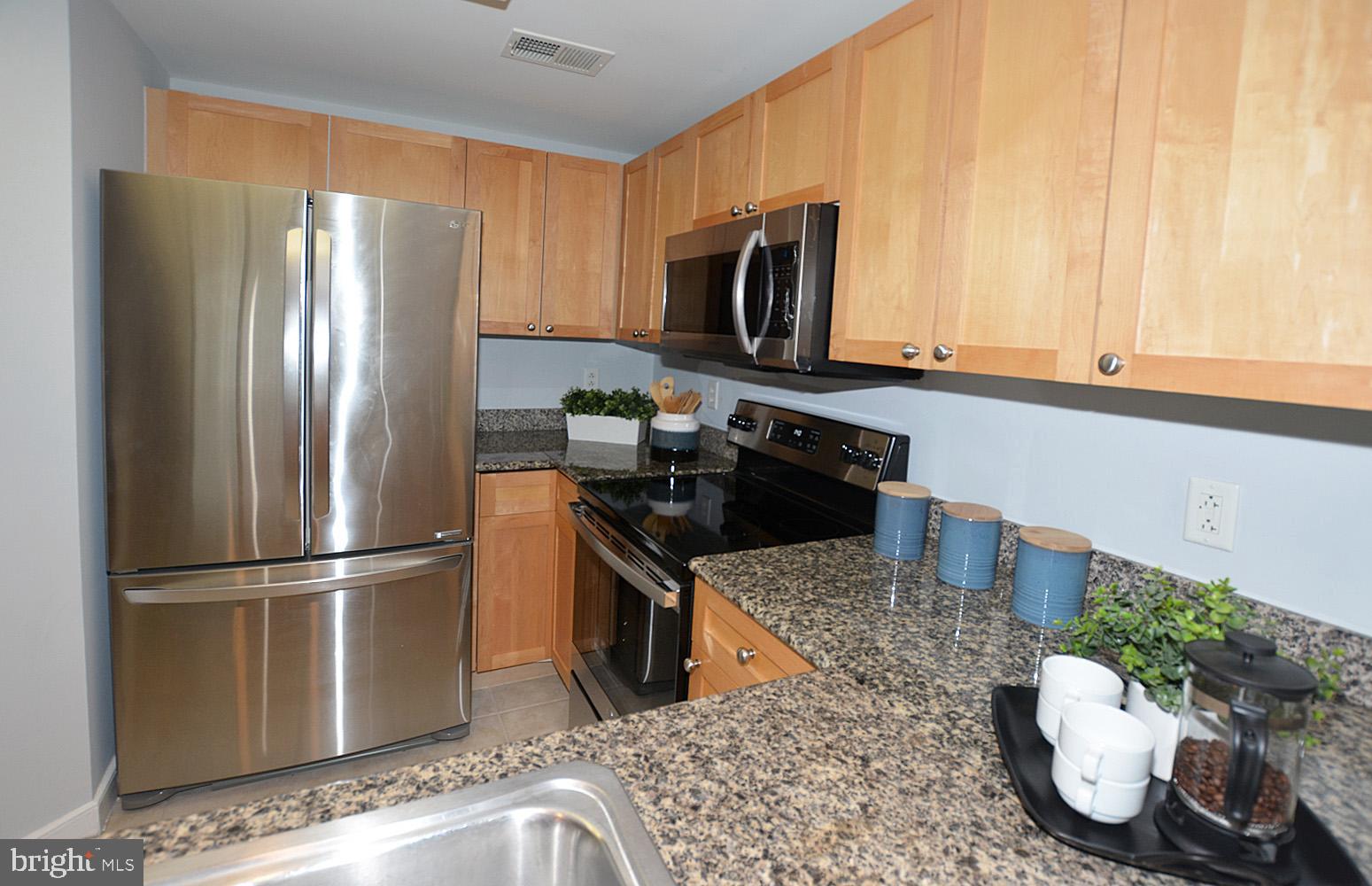 777 7th Street Northwest, Unit 1014 Washington, DC 20001 - Photo 18 of 43 a kitchen with granite countertop a refrigerator stove and microwave