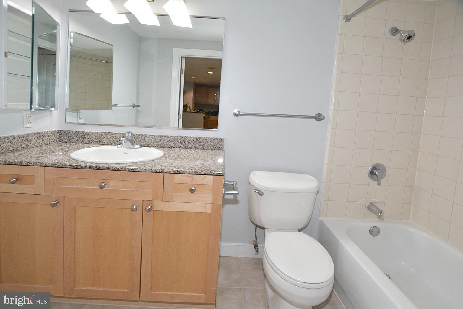 777 7th Street Northwest, Unit 1014 Washington, DC 20001 - Photo 31 of 43 a bathroom with a granite countertop toilet a sink and a mirror
