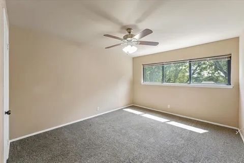 an empty room with a window and a fan