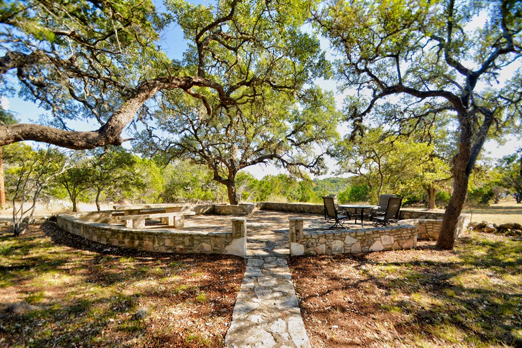 191 Coultress Road Kerrville, TX 78028 - Photo 2 of 3 a backyard of a house with table and chairs under an large trees