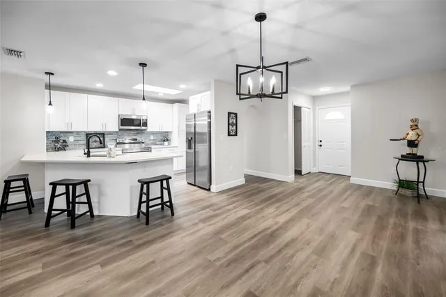a kitchen with stainless steel appliances kitchen island a dining table chairs and wooden floor